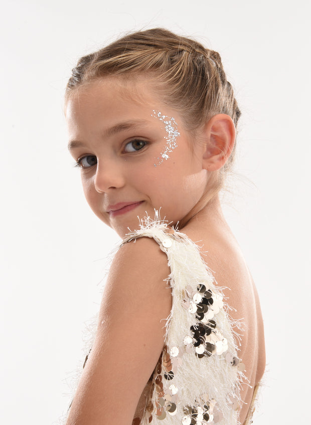 Young girl wearing a white sequined dress with a plain background