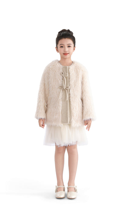 Young girl wearing a beige dress with a white lace overlay on a white background