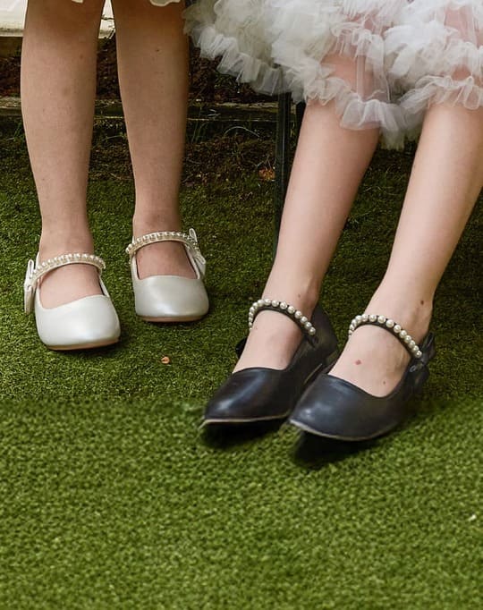 White and black pearl-strap shoes on grass